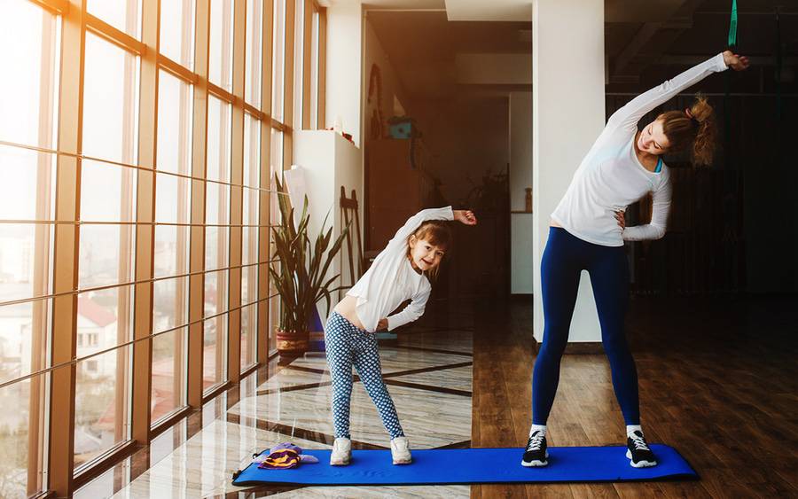 Mother teaching daughter how to exercise at home.
