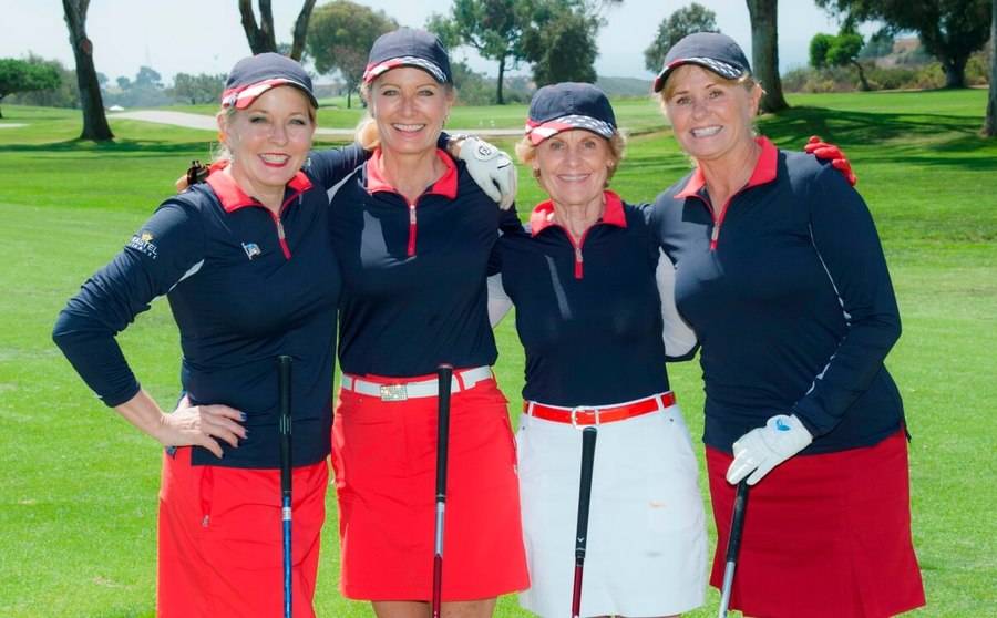 A foursome of mature female golfers smile for a photo at the Torrey Pine South Golf Course. 