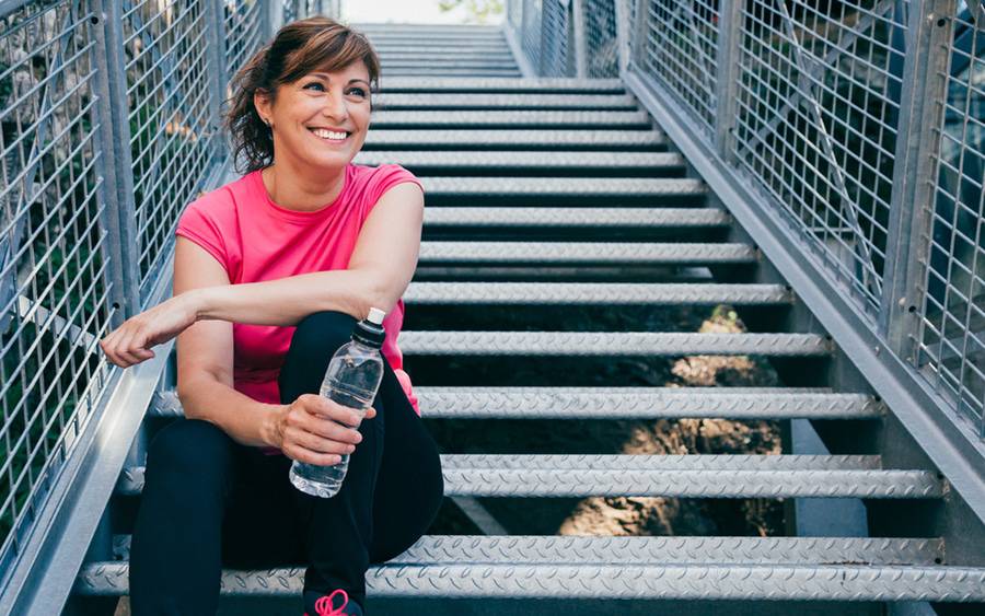A woman rests on a stairway after a workout to stay fit.