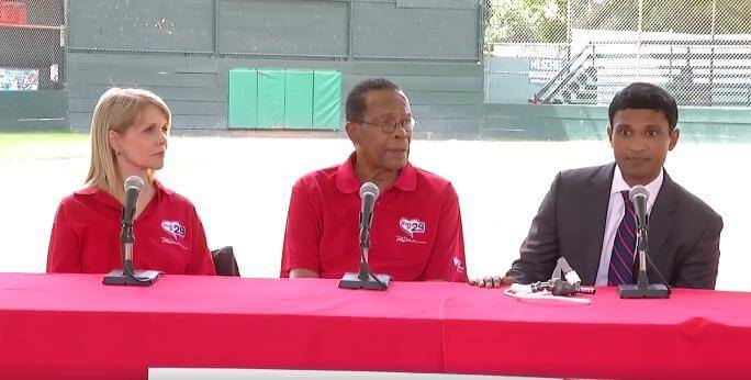 A Scripps cardiologist in a gray suit speaks at a Rod Carew (center) press conference.