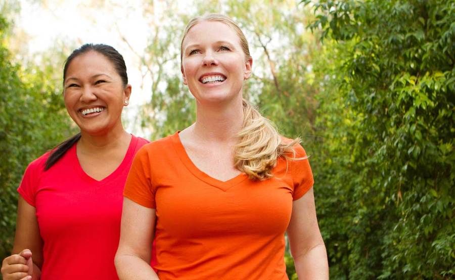 Two women smiling as the walk outdoors for exercise, representing the active lifestyle that people often enjoy after Roux-en-Y gastric bypass surgery.