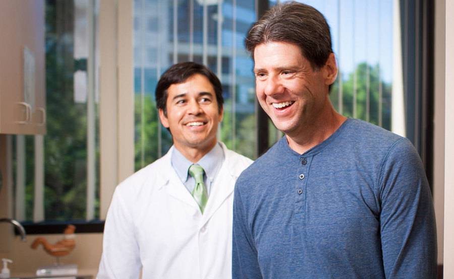 Scripps bariatric surgeon Mark Takata, MD, and a patient smiling in an exam room.