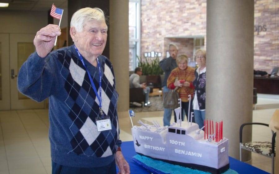 Navy vet, Ben Schulman, holds a tiny American flag and celebrates completing Scripps cancer treatment on his 100th birthday.