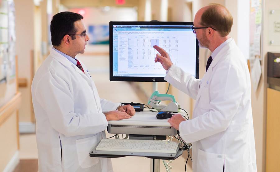 Drs. Anuj Mahindra and James Mason discuss medical information displayed on a screen, representing the advanced collaborative care at Scripps for blood and marrow transplant.