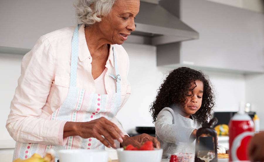 A mature woman prepares strawberries and waffles with her granddaughter, representing a healthier life with treatment for carotid artery disease.
