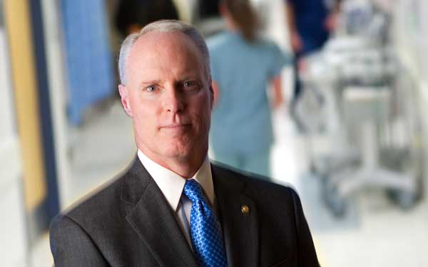 Scripps CEO Chris Van Gorder stands with quiet determination in a hospital hallway.