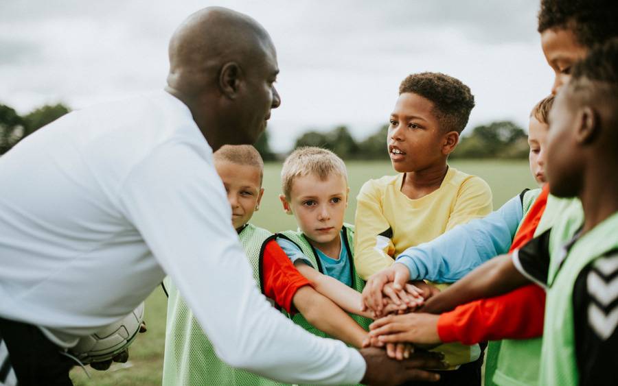 Young soccer players listen to their coach before playing.