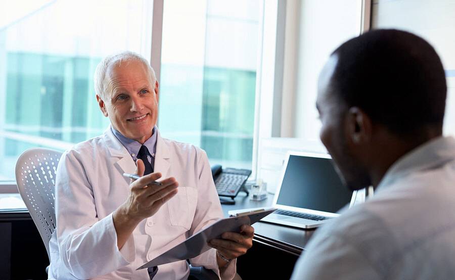 A physician talks to a 40-year-old man in a doctor's office. 