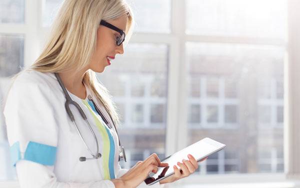 Doctor looking at tablet-600×375