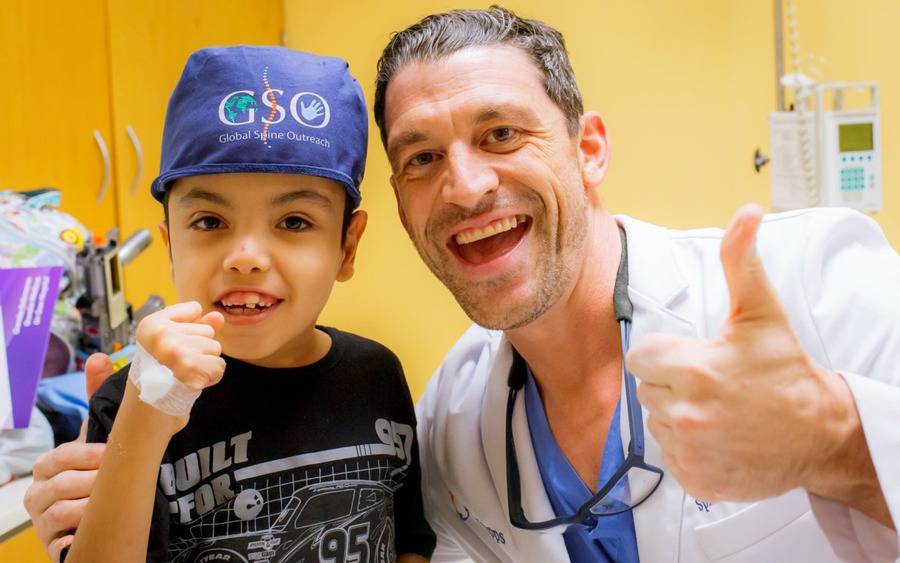 A child patient and Gregory Mundis, MD, an orthopedic surgeon, raise their arms in approval.