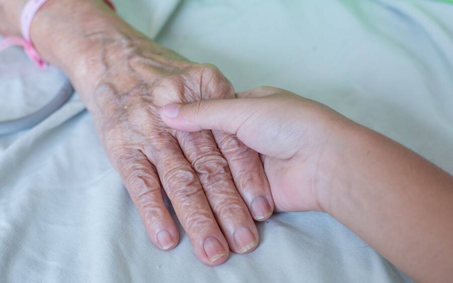 An elderly woman with an advance directive in place receives hospice care and is comforted by a loved one.