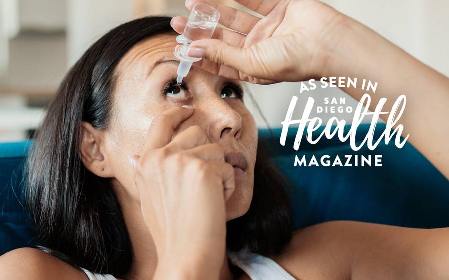 A young Asian woman looks up as she puts eye drops into her right eye - SD Health Magazine