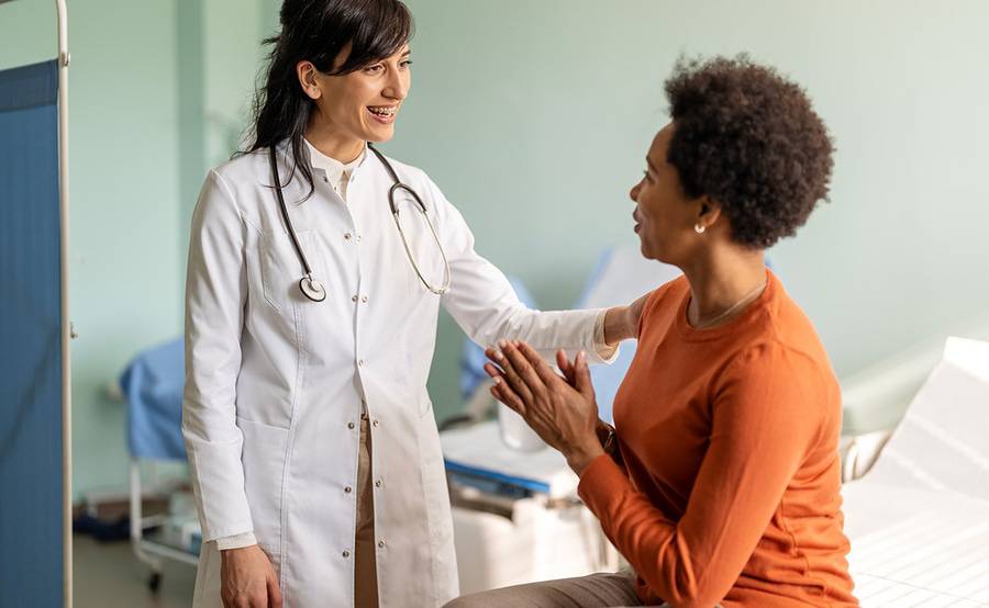 A female patient with a female provider in a clinical setting, illustrating Connect the Docs medical group providers.