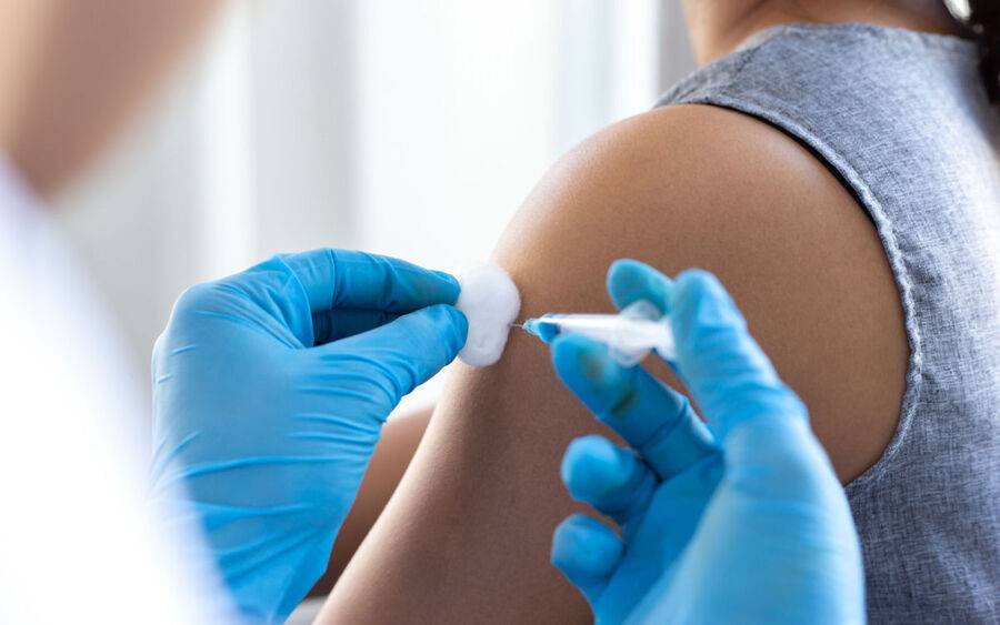 A woman gets a flu shot on her left shoulder.