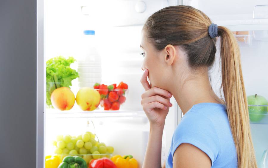 Woman with food cravings finds healthy foods in her refrigerator.