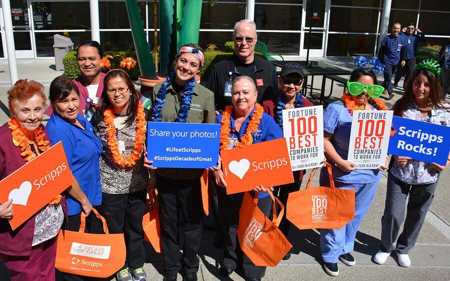 Scripps Health CEO Chris Van Gorder stands with employees holding signs about Fortune 100 Best Companies to Work For.
