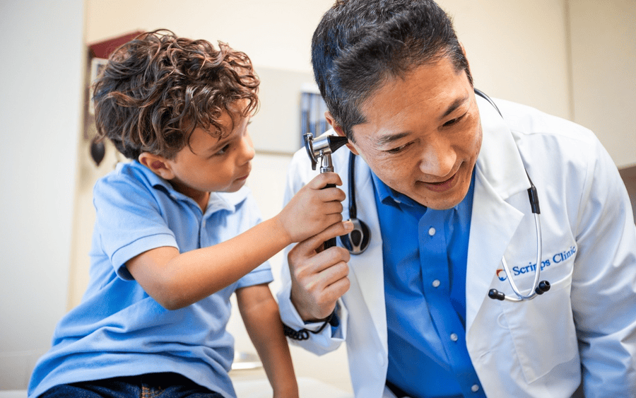 A doctor who is part of a health system lets young patient play with his stethoscope.