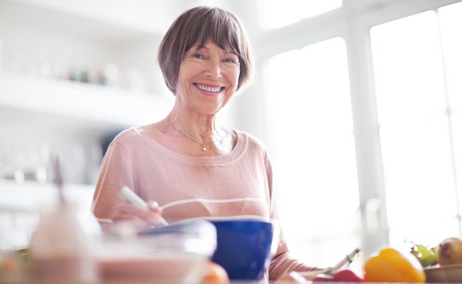 A woman smiles while preparing food in her home, representing how surgery at Scripps for gynecologic conditions can help improve quality of life for women.