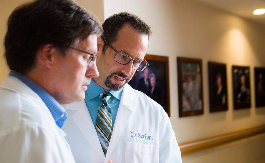 Two Scripps Health organ transplant experts have a conversation in a medical location hallway.
