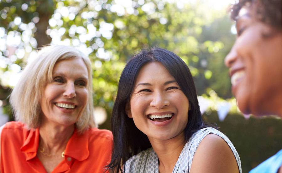 Three women smiling outdoors.