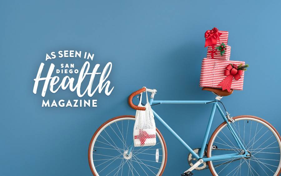 Blue bike with wrapped holiday gifts on the seat. The bike is an idea to give a gift to keep kids active to inspire physical activity to help them stay healthy - as seen in San Diego Health Magazine.