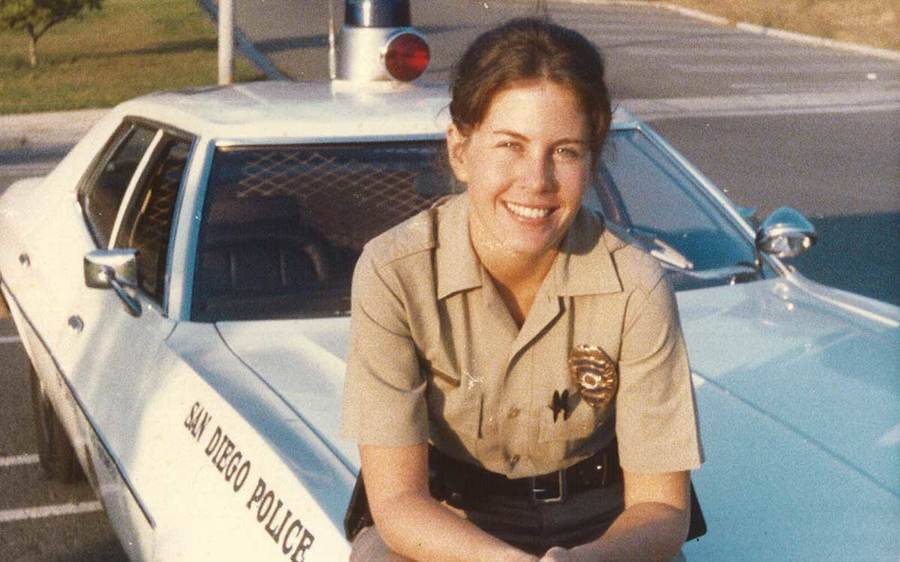 Janet Chelberg-Burgess siiting on the hood of a San Diego Police vehicle, circa 1977.