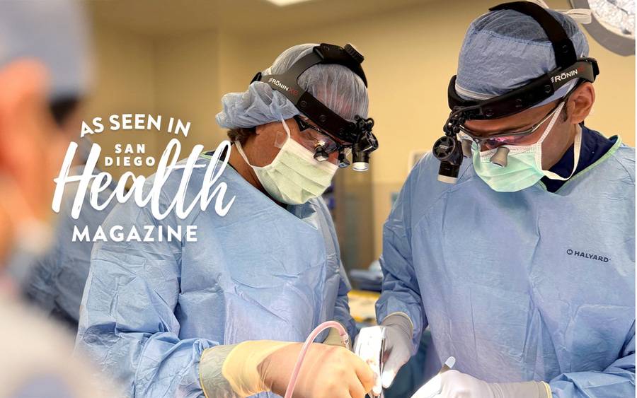 Two surgeons dressed in scrubs perform a procedure to remove a tumor. San Diego Health Magazine