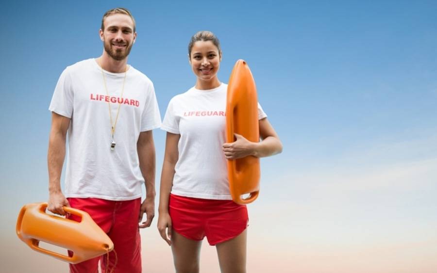 Two lifeguards pose at the beach.