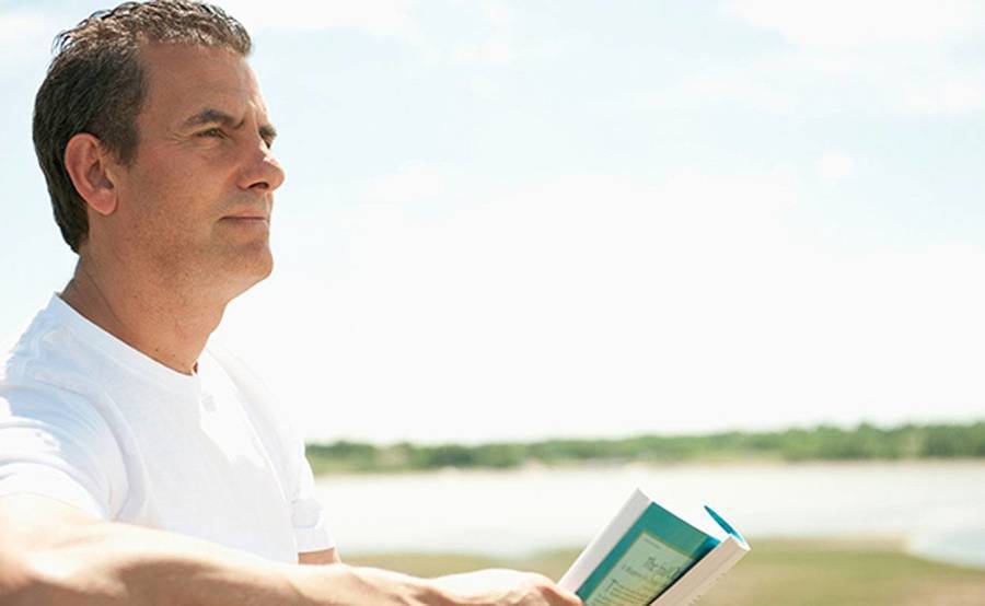 A middle-aged man by the shoreline represents the full life that can be led after lung cancer treatment.