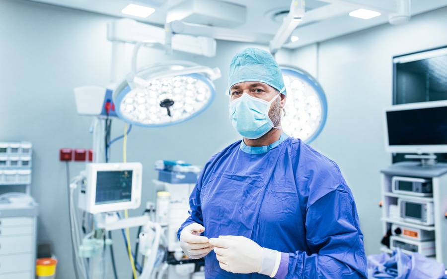 Doctor in scrubs and medical mask in modern hospital operating room.