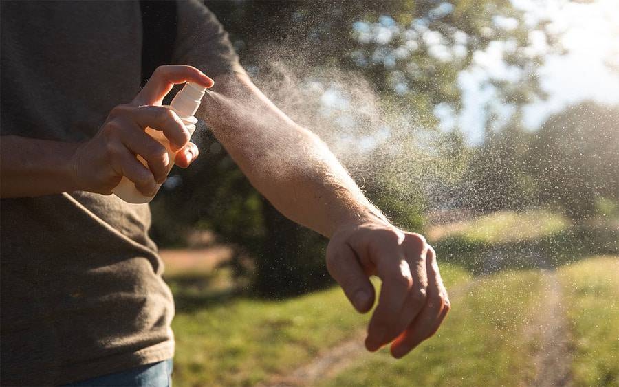 A man spraying mosquito repellent outside, illustrating how many people in San Diego can repel mosquitos.