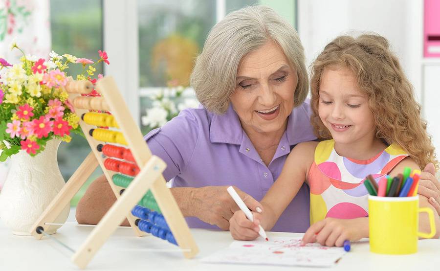 A mature woman colors with her granddaughter, representing a healthier life with treatment for mesenteric ischemia or thrombosis.