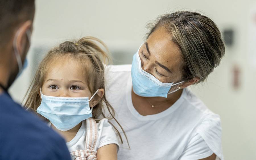 A mother and her child at an annual flu shot clinic while wearing masks.