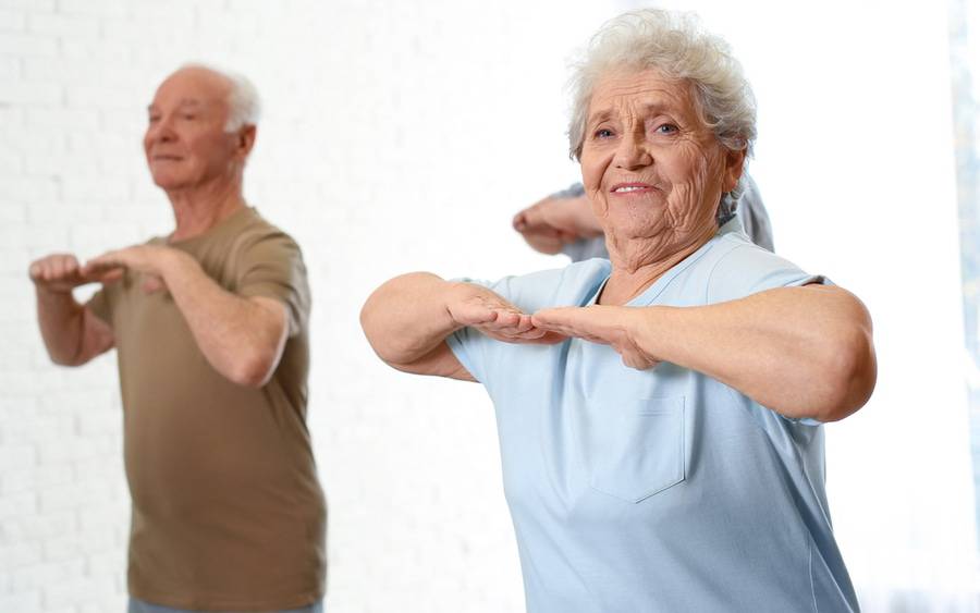 An older man and woman participate in an exercise class to improve their flexibility and strength.