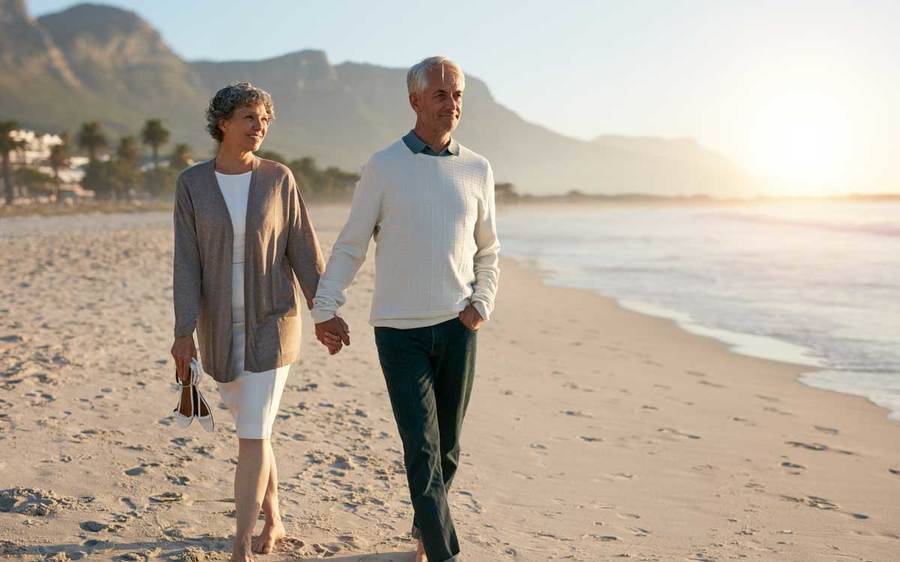A male stoke survivor strolls the beach with his wife after a landmark NIH study on stroke prevention proves effective.