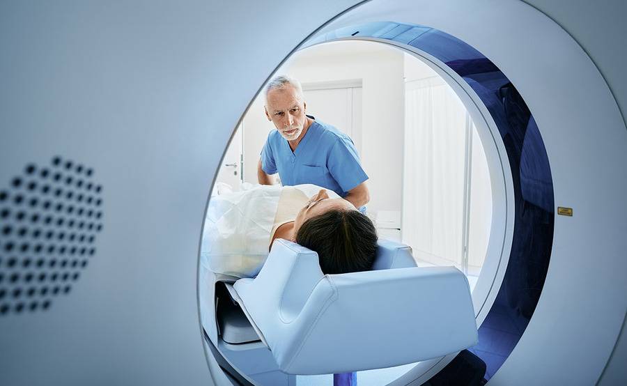 Patient in a CT machine with a provider near her, illustrating theranostics cancer treatment.