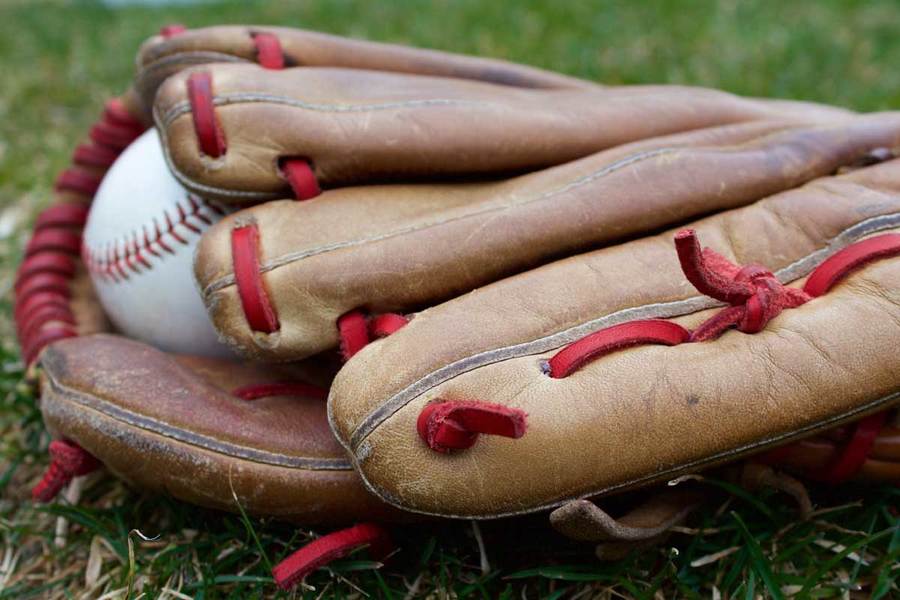 Baseball glove and baseball lying on the grass; baseball is among the sports for which athletes might jeopardize their health by taking performance enhancing supplements.