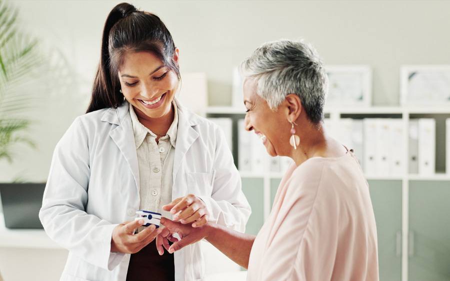 A provider checks a woman's pulse during a preventive health screening.