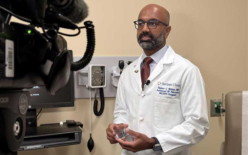 Cardiologist Rajeev Mohan, MD, standing in an exam room, speaking about the clinical trails for heart failure.