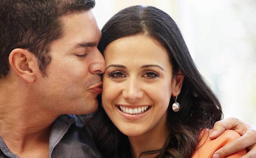 A middle-aged man kisses a smiling woman's cheek, representing the full life that can be led after reconstructive surgery.