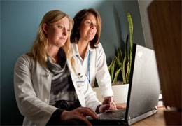 Two physician researches look at a laptop, representing ongoing studies at Scripps.