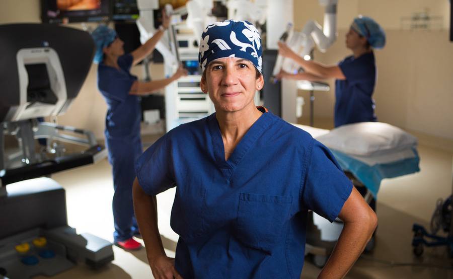 Dr. Carol Salem stands in a Scripps operating room while a team uses a robotic surgical system.