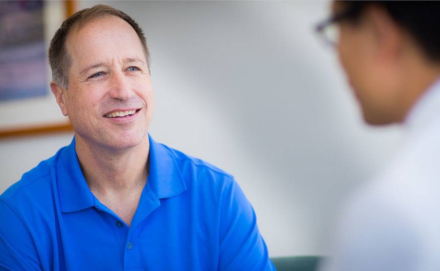 A smiling middle-aged man talks with his surgeon, representing advanced robotic prostate surgery at Scripps.