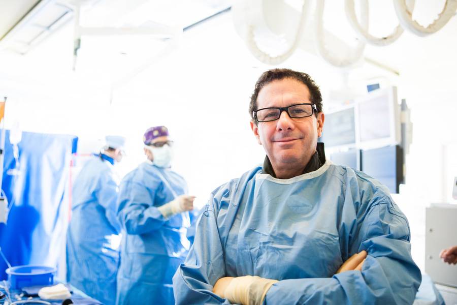 Dr. Paul Teirstein, MD, Interventional Cardiology with his arms crossed with heart doctors in the background a room.