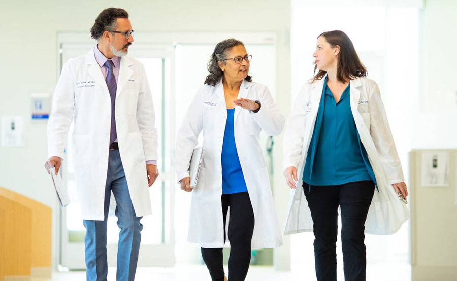 A trio of cancer doctors walk together in a hospital setting, representing why you should choose Scripps for cancer care.
