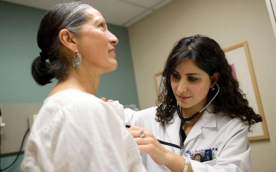 A Scripps doctor listens to the heartbeat of a mature female patient from Central San Diego.