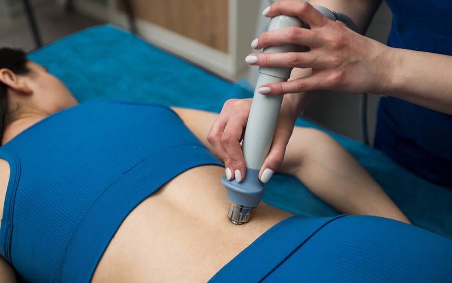 A woman receives shockwave therapy on her lower back to relieve musculoskeletal pain.