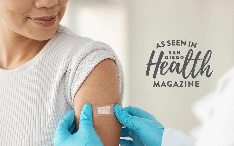 A health care provider puts a band-aid on a female patient's arm after administering a shot.