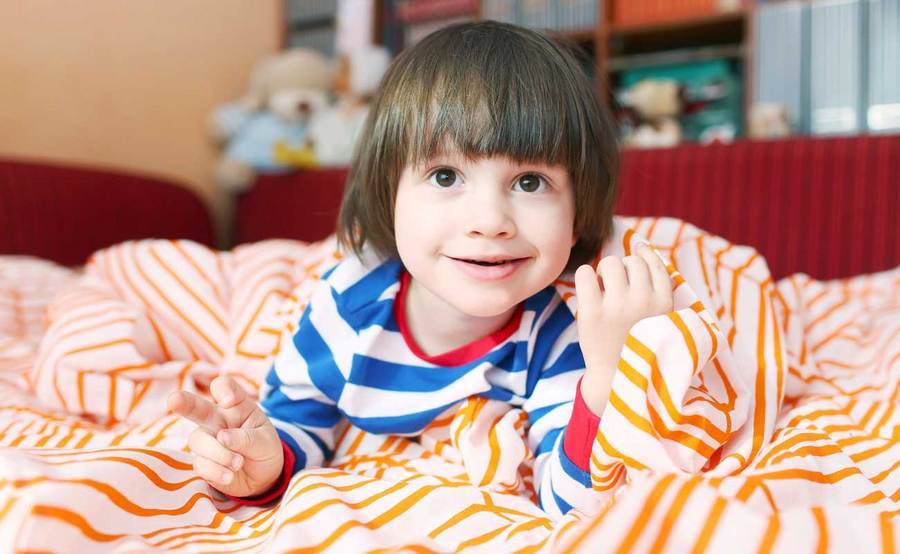 Smiling child in striped pajamas gets ready for bed.