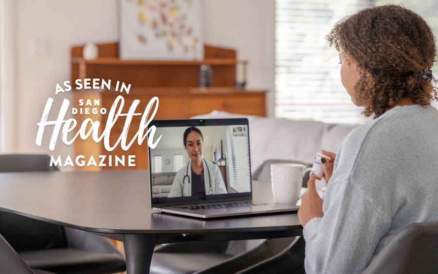 A woman sits at a table while she meets with her doctor virtually on a laptop computer and discusses medication. SD Health Magazine